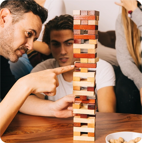 Gruppo di giocatori che osserva una torre di blocchi durante una serata di giochi